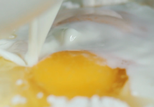 意大利手工水饺,拿个碗,倒入面粉,打两个鸡蛋进去,加盐和牛奶,和匀。