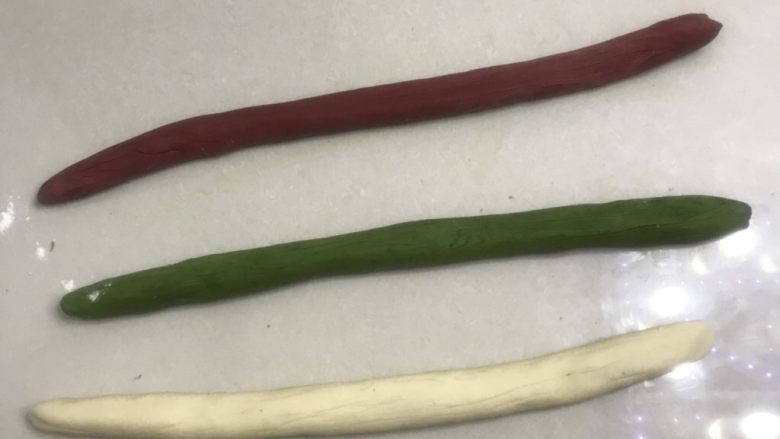 圣诞花环面包,8把三个面团分别拿出来,拍打面团排气,整理成长条形,用二手掌慢慢搓长。