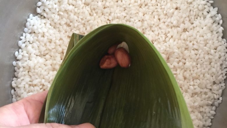 肉粽子,用手托住粽叶,放入两枚花生根据你自己口味,放不放都可以