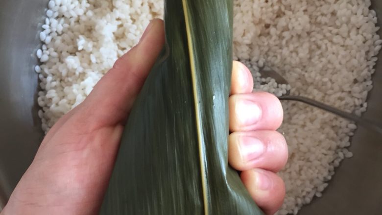 肉粽子,另一只手辅助,把左边的叶子也压下来