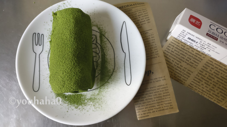 抹茶毛巾卷,取出冷藏的毛巾卷,一小勺抹茶粉用细筛子筛在表面,抹茶粉的用量不在配方中;
裁一张漂亮的油纸,宽度是毛巾卷的1/3,包起来即可