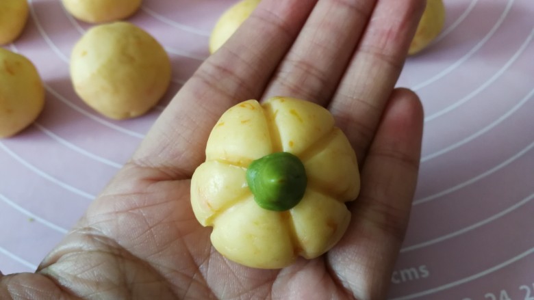 南瓜饼干,把绿色的小面丁整理成水滴状,底部粘一点水组装在做好的南瓜面团顶部中间,一个南瓜饼干生坯就做好了