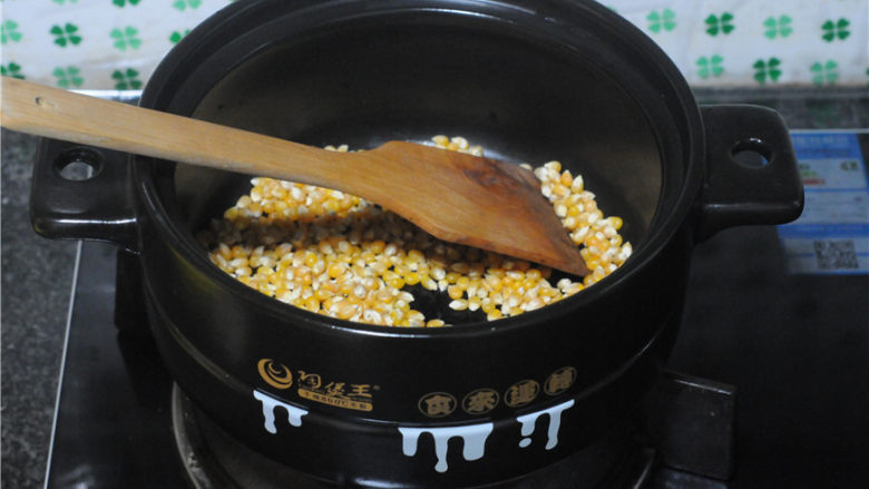 砂锅爆米花,随着温度不停上升,用木质的铲子不停地搅拌,让玉米均匀受热