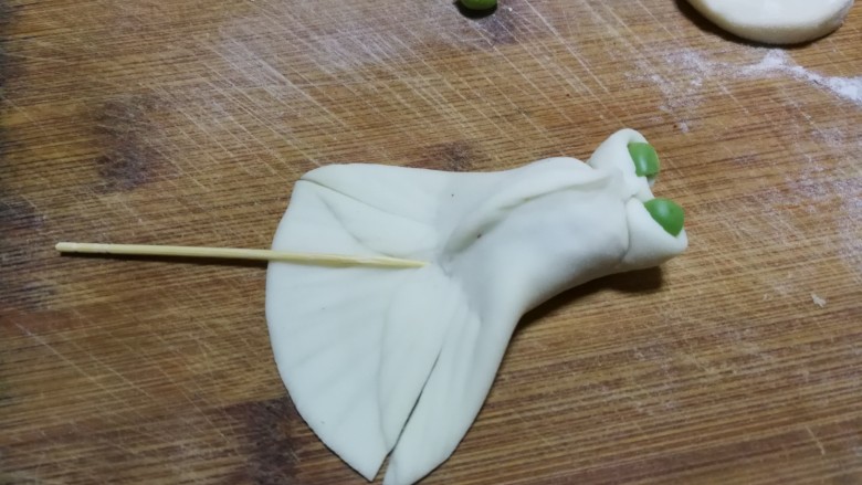 金鱼饺子,前段中间往里面收,捏成两个小孔当作金鱼眼睛,分别在小孔里面放两粒小<a style='color:red;display:inline-block;' href='/shicai/ 148'>豌豆</a>,尾巴处先用牙签压出花纹印记,然后在尾巴处对称切两刀,分割出鱼鳍部分