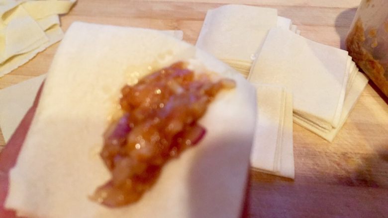 乡味~重庆小吃红油抄手,手拿一张面皮放入肉馅。