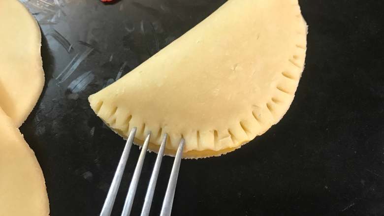 芥末果酱饺子派,然后对折起来,捏紧后用叉子在边缘压出花纹。