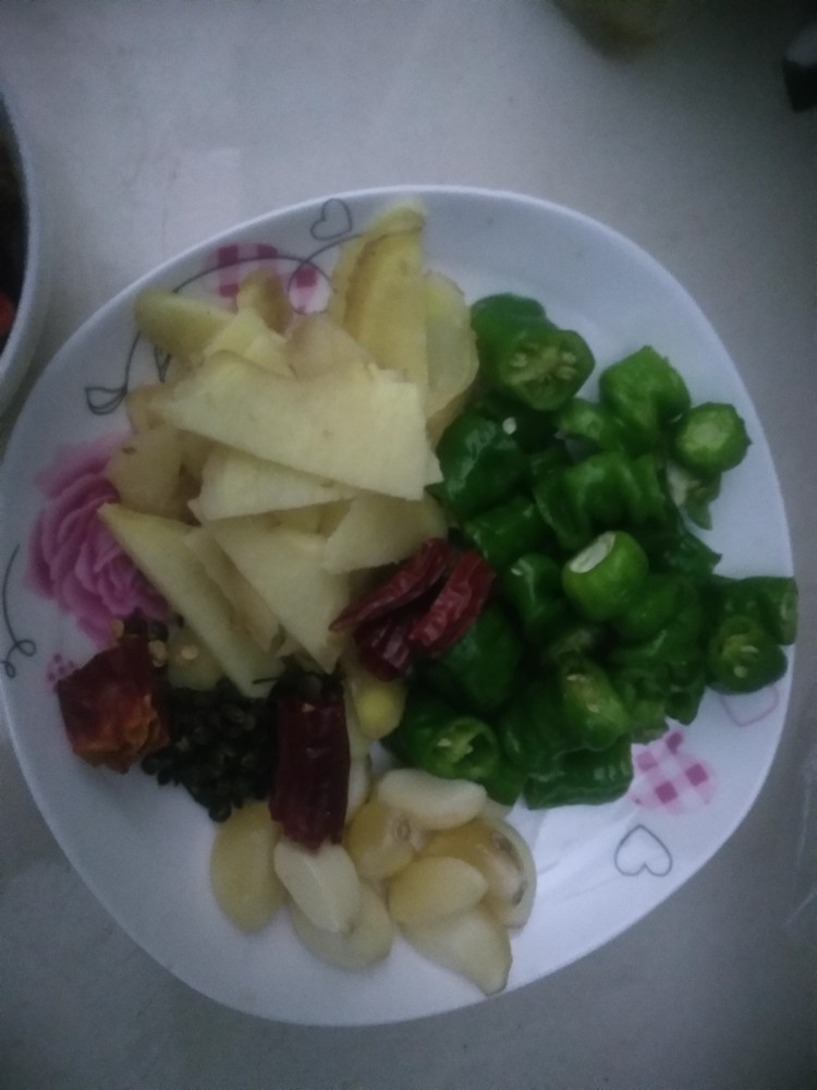 家庭版孜然烤鱼,准备材料。,姜切片,大蒜剥皮,青椒切段,加花椒放盘子备用,另外同时准备好洋葱切丝,泡椒酸豆角,孜然粉,细红辣椒面,以及豆瓣酱。