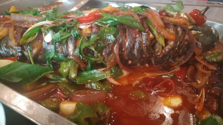 家庭版孜然烤鱼,这个时候鱼也差不多蒸好了,把刚刚做好的配菜均匀的淋在鱼上面,撒点香菜,大葱。