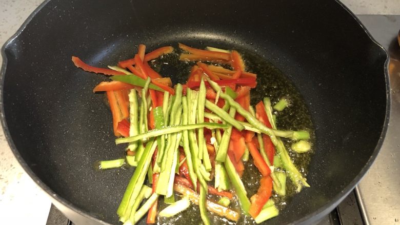 三彩手撕金针菇,接着加入青椒红椒丝,继续翻炒