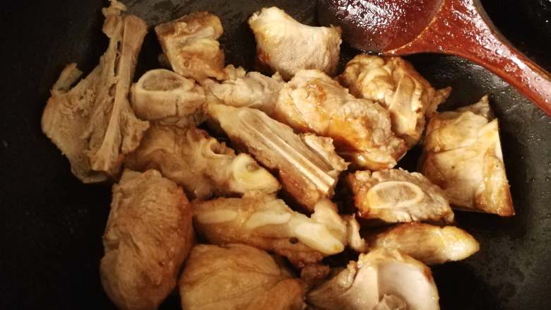 吮指酱棒骨,把沥干的棒骨倒入糖浆中,翻炒使之棒骨裹上糖色
