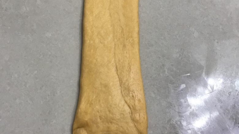 南瓜烫种炼乳吐司,15翻面再用擀面杖擀一下,整理成大约长30厘米,宽7厘米。