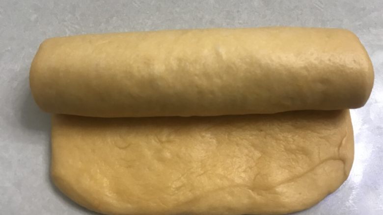 南瓜烫种炼乳吐司,11从上而下卷成长条型,放入烤盘。