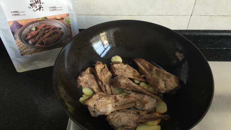 干锅土豆鸭头,倒入解冻的老卤鸭头翻炒半分钟左右;