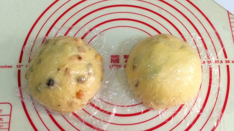 圣诞面包史多伦,把发好的面团取出排气,然后分成两等份,滚圆松弛15分钟,记得盖好保鲜膜。
