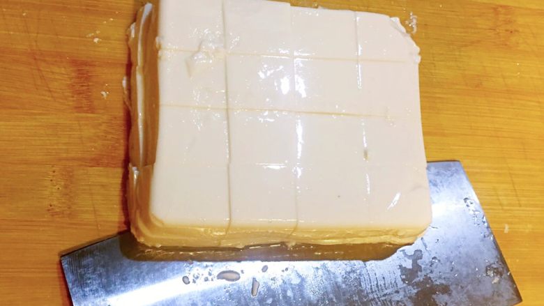 麻婆豆腐,右手把刀的侧面放在豆腐底部,左手轻扶豆腐表面,把豆腐从砧板上移到盘中