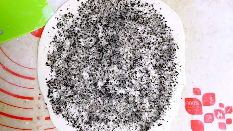 发面黑芝麻糖饼,取其中一个小面团擀成1元硬币厚度的面片。
撒一层黑芝麻糖馅。