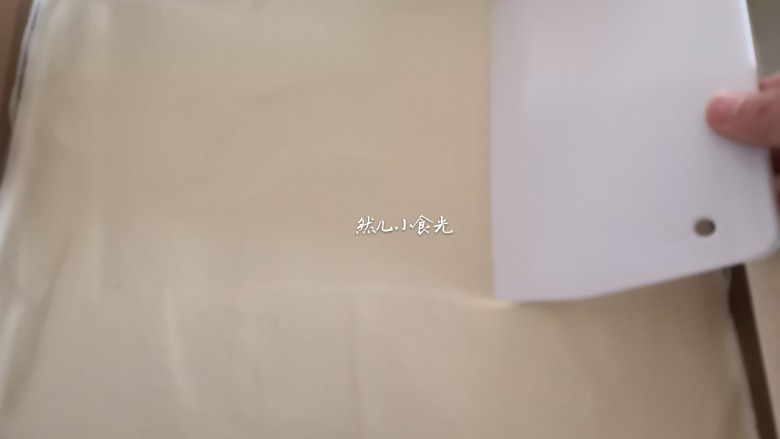 芒果蛋糕卷,用刮刀抹平表面,震一下模,将气泡震出。