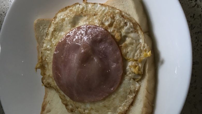 快手早餐之两分钟搞定的简易三文治,把煎蛋放在上,再加一片火腿