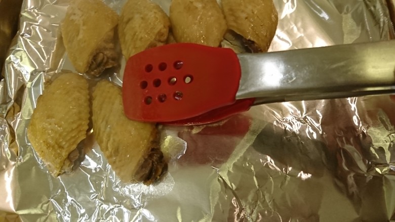 香草雞翅,撈出已微微上色煮熟的雞翅,擺到烤盤排好