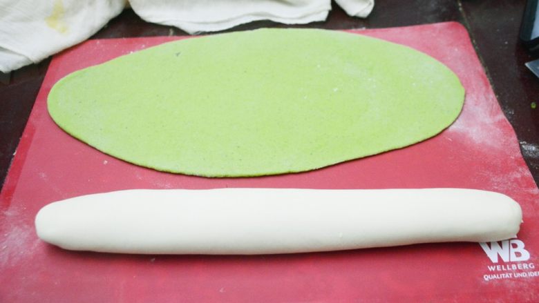 翡翠菠菜饺子,醒发好的面团拿出揉好,绿面团用擀面杖擀成椭圆的一快面皮,白面团揉成长条的面团