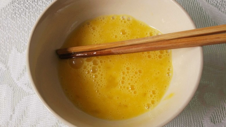 菠萝炒饭,鸡蛋敲入碗中,加适量盐,用筷子打散。