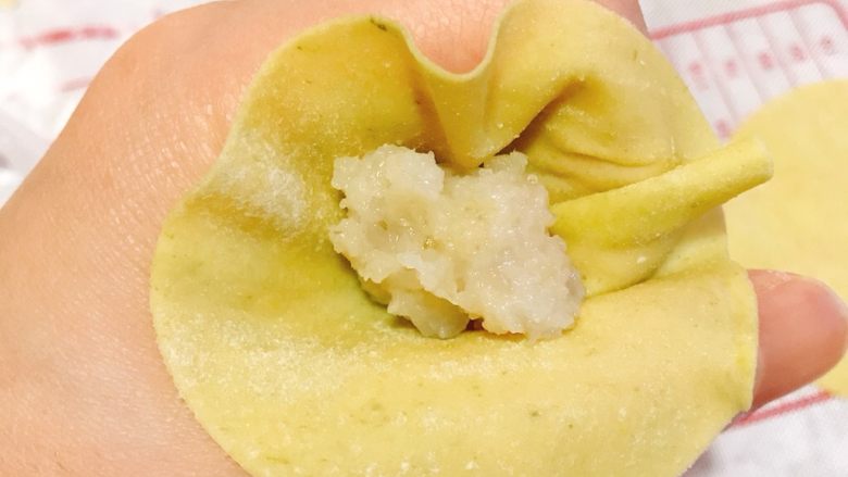 马蹄鲜虾小馄饨,将面皮放到虎口,再取一点馅料放到面片中心收拢。