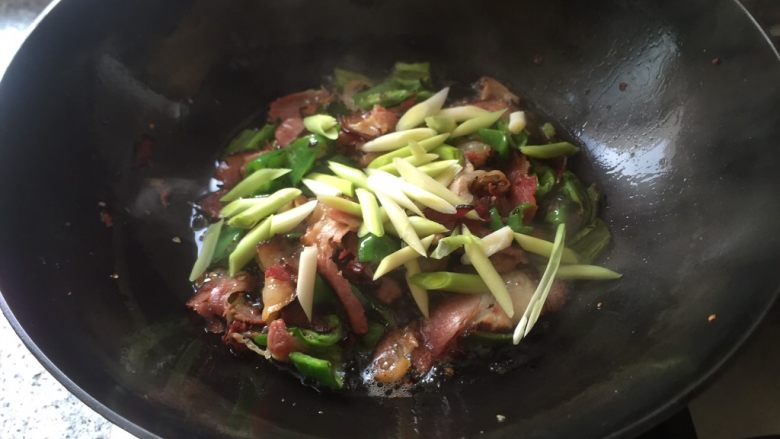 乡味十足➕重庆~烟熏腊肉炒蒜苗,加入辣椒,蒜苗。