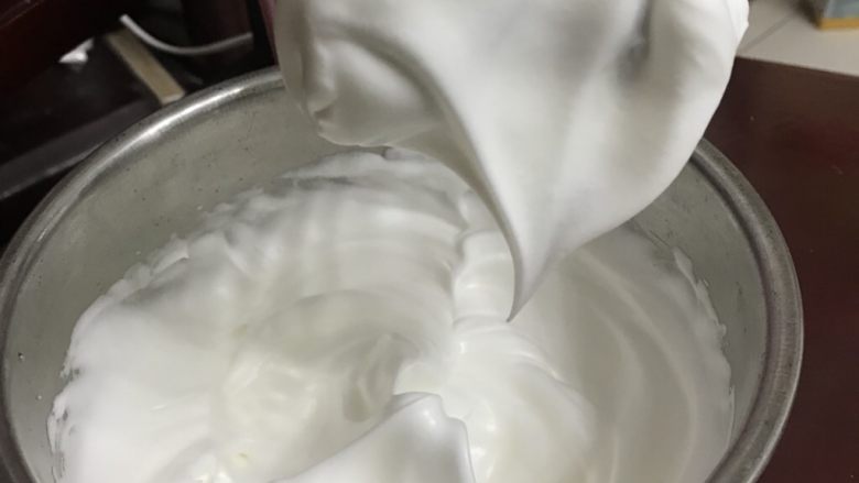 柠檬香戚风纸杯蛋糕,用电动打蛋器中高速打至拿起打蛋头有大弯钩状态时,全部加入剩下的白砂糖。