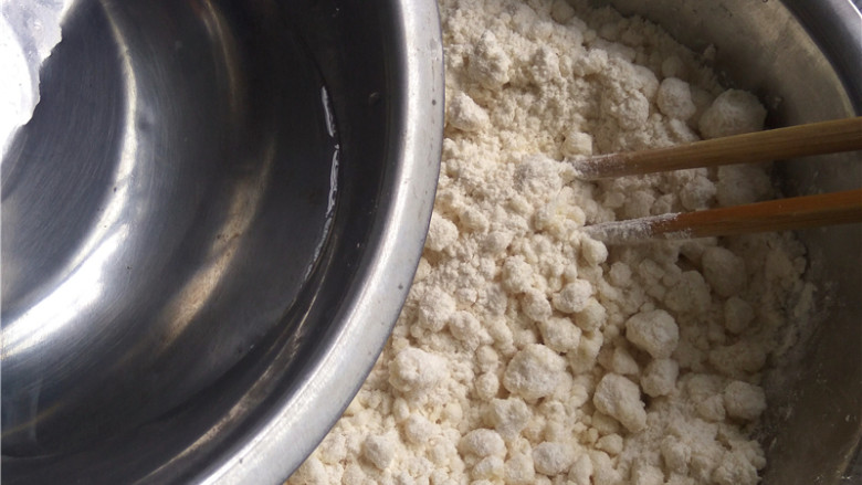 玉米煎饼,徐徐倒入适量清水;一边倒入清水,一边用筷子划圈搅拌;