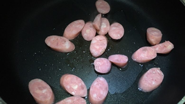 双菇炒热狗,锅中倒入油,放入热狗,先用中小火煎一面金黄