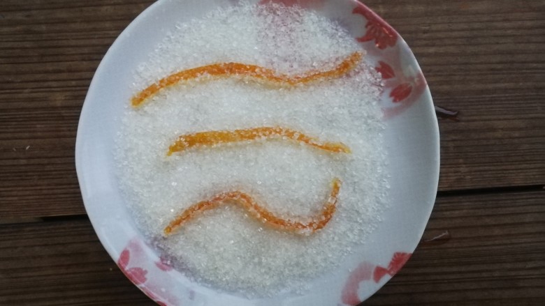 糖渍橙皮,盘子里倒适量白砂糖,放凉的橙皮依次在白砂糖里滚一圈,裹上一层砂糖