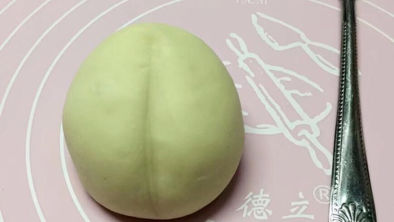 寿桃馒头,然后双手转动面团,将馒头捏成桃子形状,再用勺子把压出桃子中间的痕。