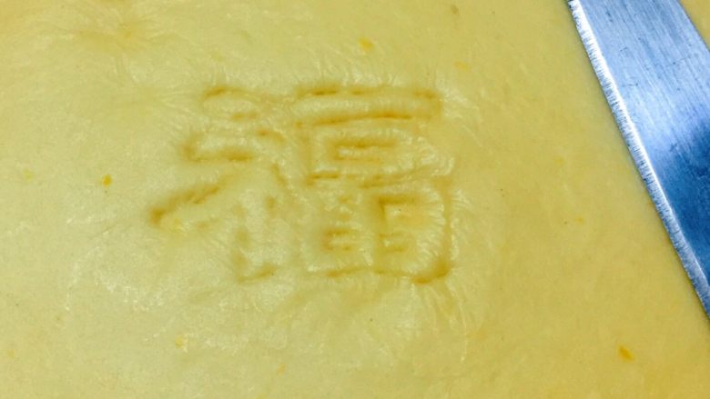 福袋馒头,如图:取一黄色面团擀成薄面片,用小刀的刀背轻轻地刻写出一个福字。