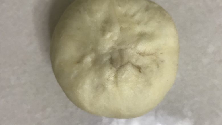 奶香豆沙小餐包,用虎口收小接口,再捏紧接口,翻面