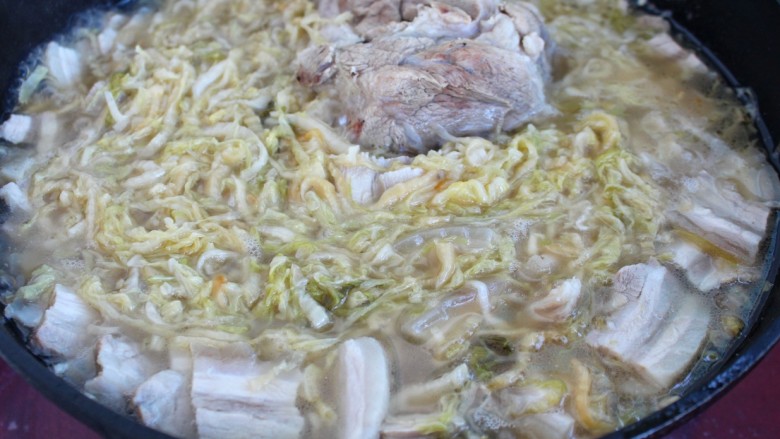 东北酸菜猪肉炖粉条,再倒入炖大骨头的肉汤煮开,改小火炖半个小时