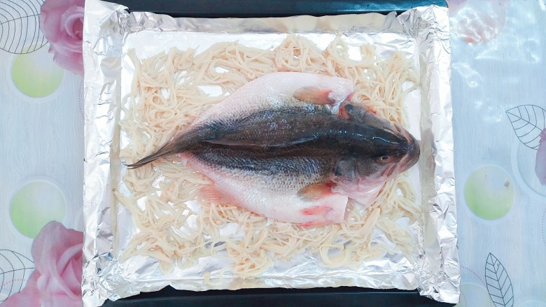 纸包烤鱼,接下来把腌制好的鲈鱼铺在放有金针菇的烤盘里!