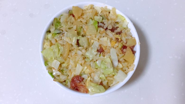 卷心菜腊肠炒饭,米饭装入小碗中,用铲子压紧