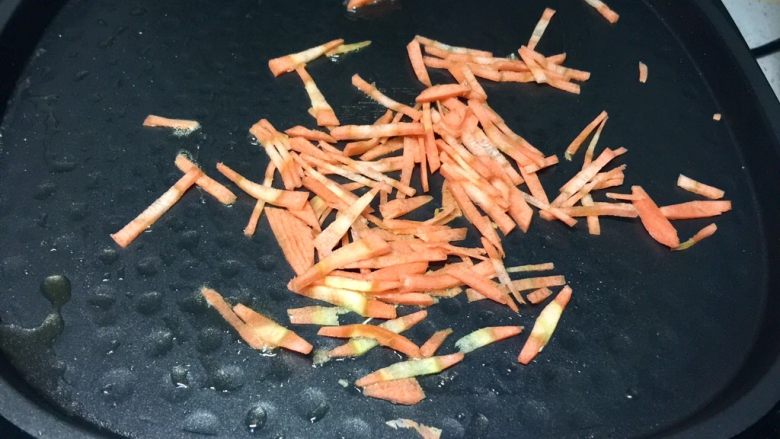黄金黑米卷,电饼铛留底油,先放入胡萝卜丝翻炒。