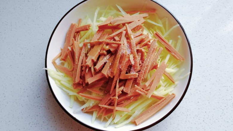 火腿土豆烘蛋,火腿与土豆丝放入盘子中,调入少许盐和<a style='color:red;display:inline-block;' href='/shicai/ 756'>鸡精</a>;