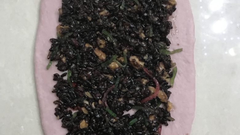 紫薯紫米核桃软欧,取一个面团收口朝上,从中间向二头左右擀开边上的气泡用手有掉。
11放上紫米馅直接用筷子压几下。自己做的喜欢放多少就放多少。