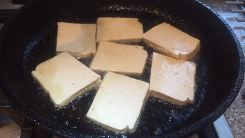 香辣西芹炒豆干,平底锅放烧热,放入豆腐片小火煎。