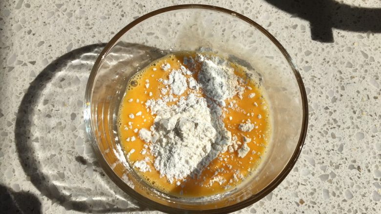 日式泡芙蛋糕卷,【克林姆馅制作】碗中放入打匀的蛋液,加入低筋面粉与玉米淀粉,用蛋抽混合均匀