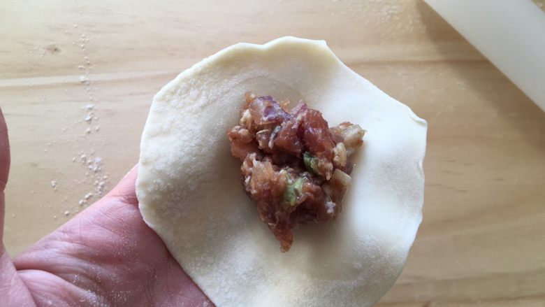 手工牛肉水饺,取出冰箱里的牛肉馅儿,用勺子舀一小勺到饺子皮中间