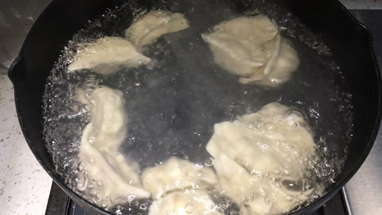 手工牛肉水饺,坐一锅热水,水微沸腾时倒入饺子,第一次水煮沸腾后加入适量清水,等待第二次沸腾,然后再加一次凉水继续煮,这次盖上锅盖,主要要守着锅,以免水沸腾扑出来。(前两次水沸腾是为了煮熟饺子皮,最后一次加盖为了馅熟透)