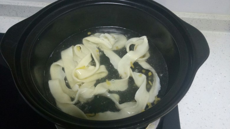 羊肉卷烩面,水开后,扯入1片烩面。