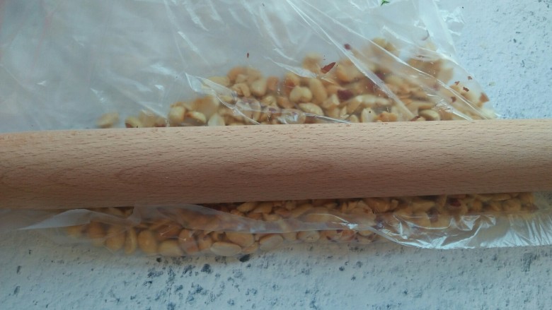 步步高菠菜塔,将花生放在保鲜袋中,用擀面杖压碎。