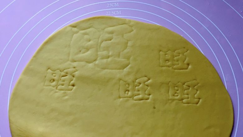 新年旺旺旺,然后取黄色面团擀成1cm厚的面片,用美工刀轻轻地刻写出一个大 “旺 ”、4个小 ”旺”的字样。