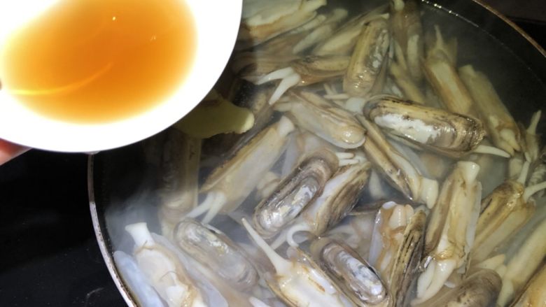 蒜泥烤蛏子,将适量水烧开放入盐、料酒、姜片,清洗干净的蛏子放入其中煮沸。捞出飞过水的蛏子。