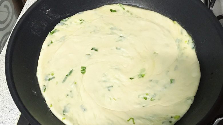 葱油饼,锅底放油,小火,放入饼,旋转一下,使油均匀涂抹在饼上。