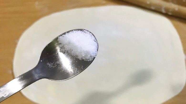 葱油饼,撒半勺盐,用手摸匀,轻轻把盐拍进面饼里。